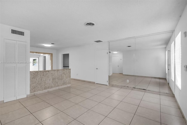 spare room with light tile patterned flooring and a textured ceiling