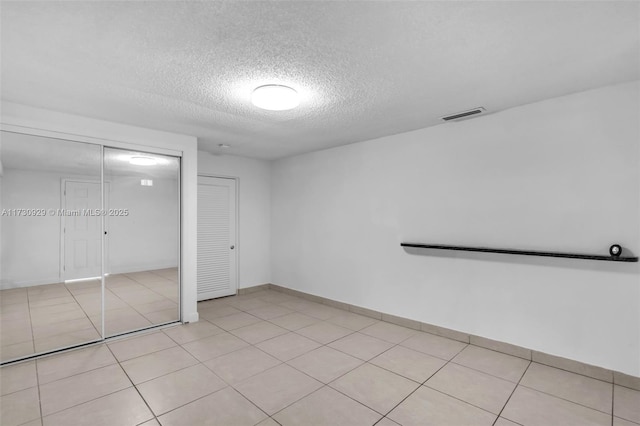 unfurnished bedroom featuring light tile patterned floors, a textured ceiling, and a closet