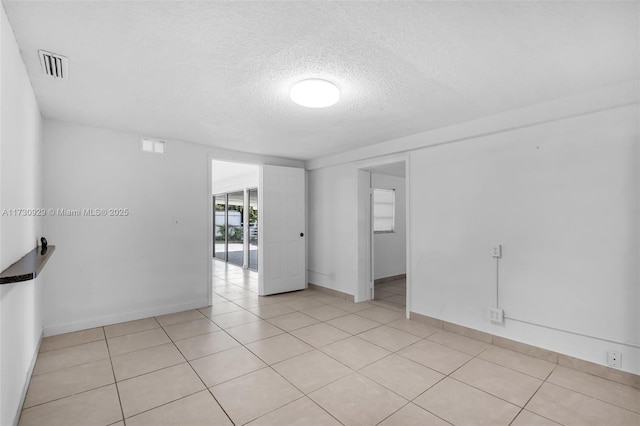 unfurnished room featuring light tile patterned flooring and a textured ceiling