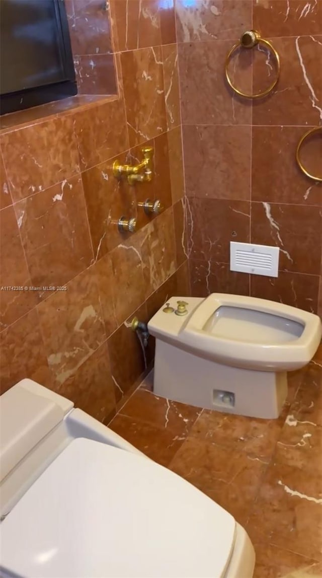 bathroom featuring toilet and tile walls