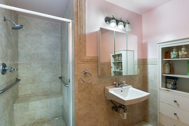 bathroom with an enclosed shower, sink, and tile walls