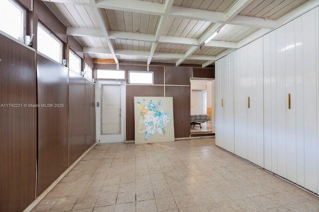 interior space featuring beam ceiling, wooden walls, and a healthy amount of sunlight