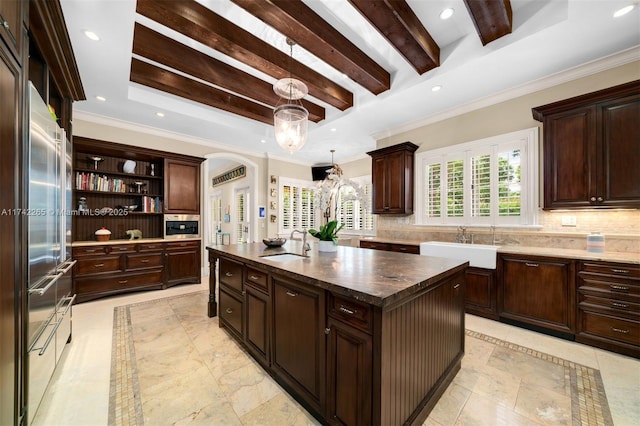 kitchen featuring sink, decorative light fixtures, dark brown cabinets, a kitchen island, and decorative backsplash