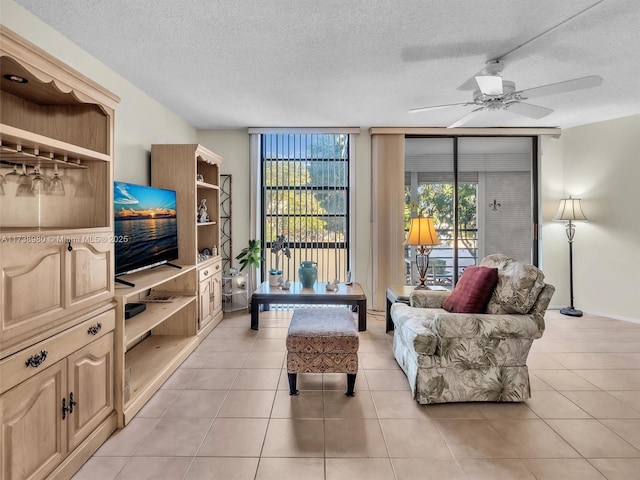 living room with ceiling fan, floor to ceiling windows, a textured ceiling, and light tile patterned flooring