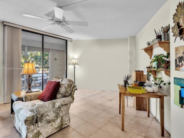 tiled living room featuring expansive windows, ceiling fan, and a textured ceiling