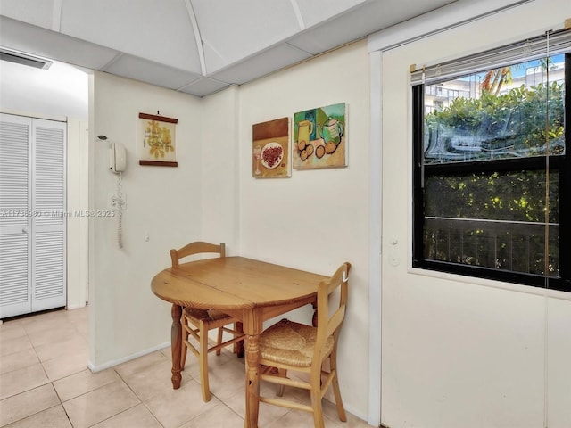 tiled dining space with a drop ceiling