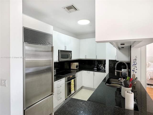 kitchen featuring stainless steel appliances, white cabinetry, sink, and decorative backsplash