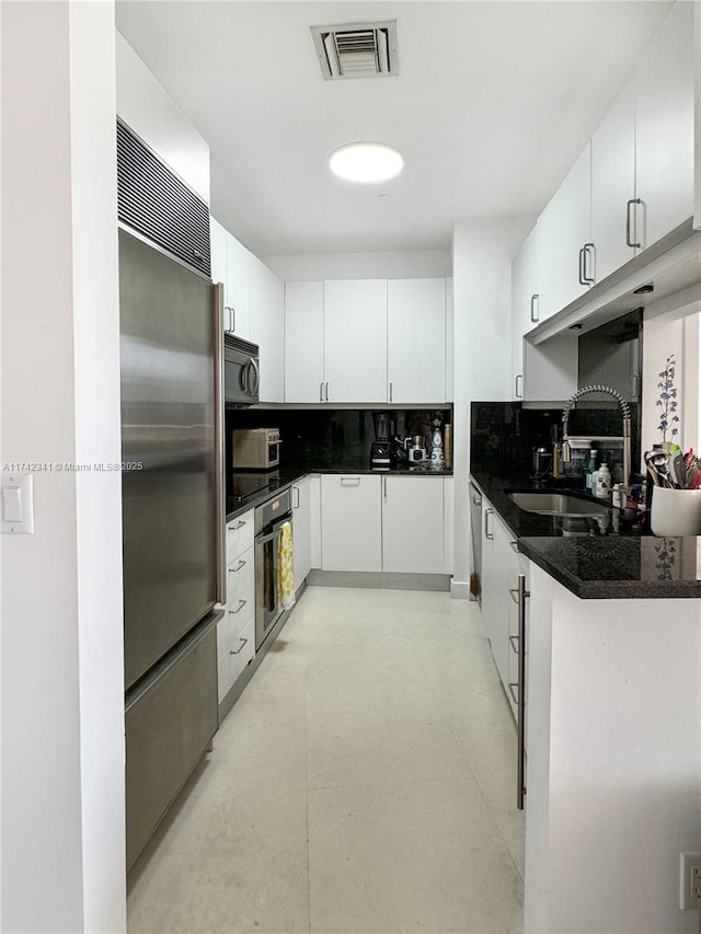 kitchen with white cabinetry, sink, decorative backsplash, and stainless steel appliances