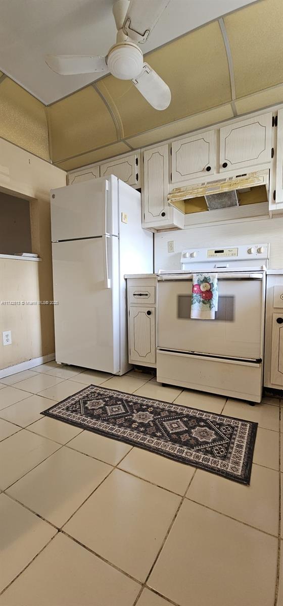 kitchen featuring white cabinetry, light tile patterned floors, ceiling fan, and white appliances