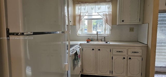 kitchen with fridge, sink, decorative backsplash, and white range with electric cooktop