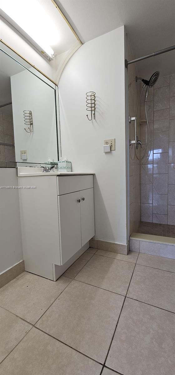 bathroom featuring vanity, tile patterned flooring, and a tile shower