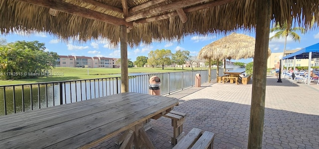 wooden deck with a gazebo, a water view, and a patio area