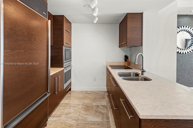 kitchen featuring track lighting, built in appliances, and sink