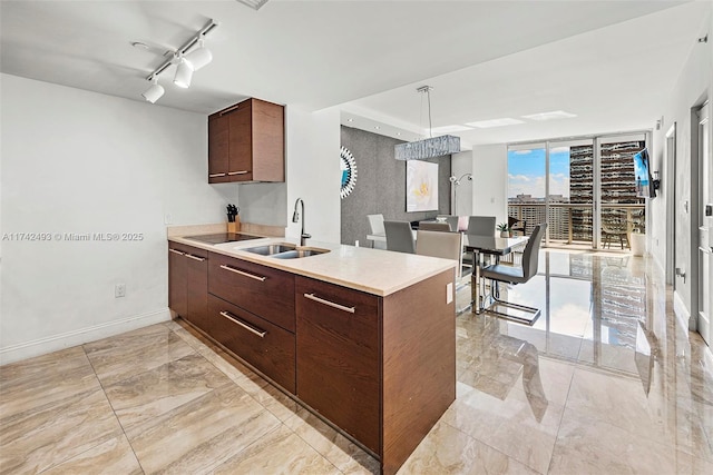 kitchen featuring sink, hanging light fixtures, black electric cooktop, track lighting, and a wall of windows