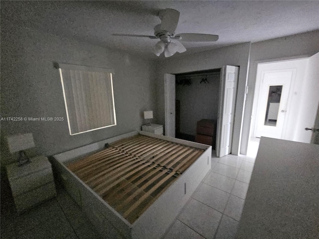 bedroom featuring ceiling fan, a textured ceiling, a closet, and light tile patterned floors