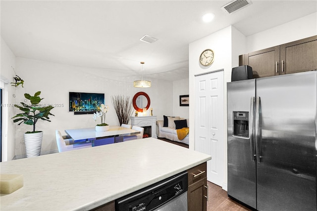 kitchen with hanging light fixtures, appliances with stainless steel finishes, dark brown cabinets, and dark hardwood / wood-style floors