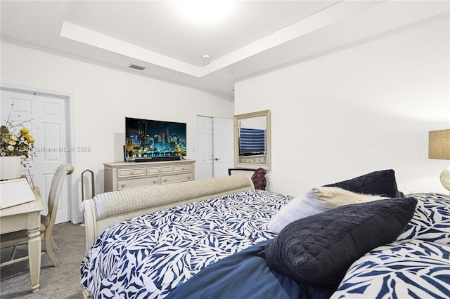 carpeted bedroom with a raised ceiling