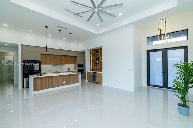 kitchen with black refrigerator, a spacious island, hanging light fixtures, a high ceiling, and french doors