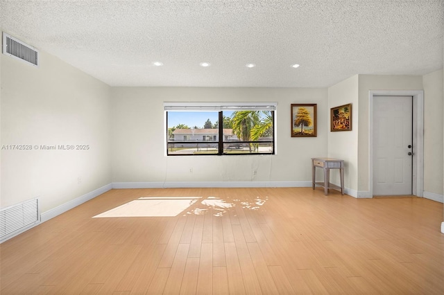 spare room with light hardwood / wood-style flooring and a textured ceiling