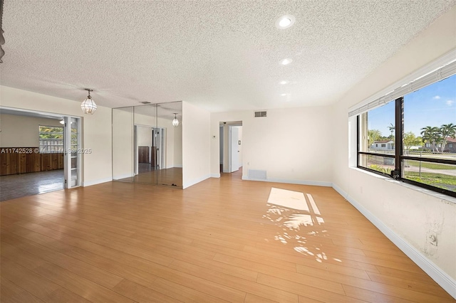 empty room with a textured ceiling and light wood-type flooring