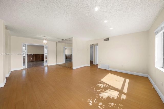 unfurnished living room featuring hardwood / wood-style floors and a textured ceiling