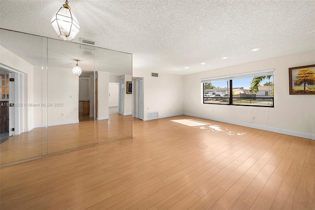 unfurnished room with a textured ceiling and light hardwood / wood-style floors