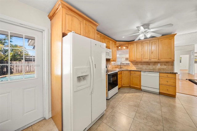 kitchen featuring a wealth of natural light, sink, light stone counters, and white appliances