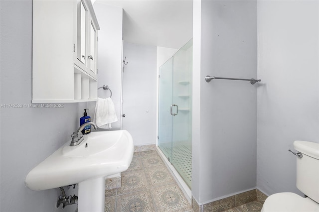 bathroom featuring toilet, a shower with shower door, and sink