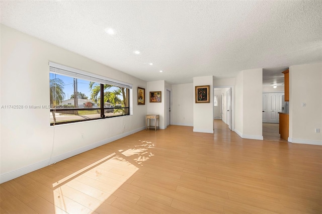 unfurnished living room featuring light hardwood / wood-style floors and a textured ceiling