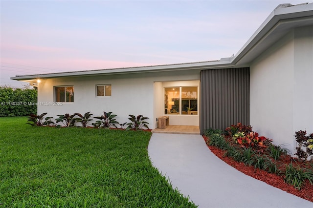 exterior entry at dusk featuring a lawn