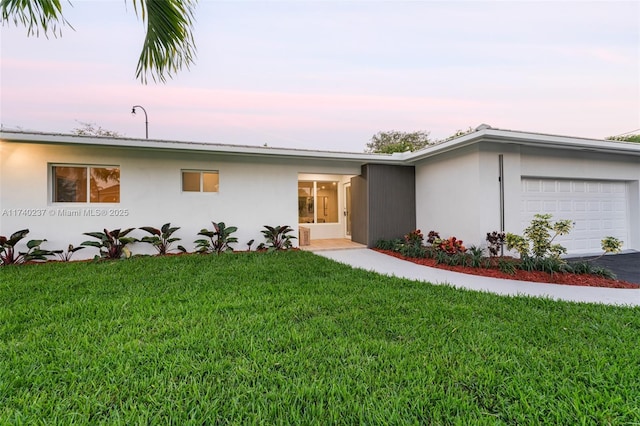 ranch-style house featuring a garage and a lawn