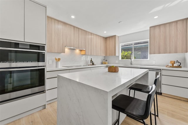 kitchen with white cabinetry, a kitchen island, a kitchen breakfast bar, and appliances with stainless steel finishes