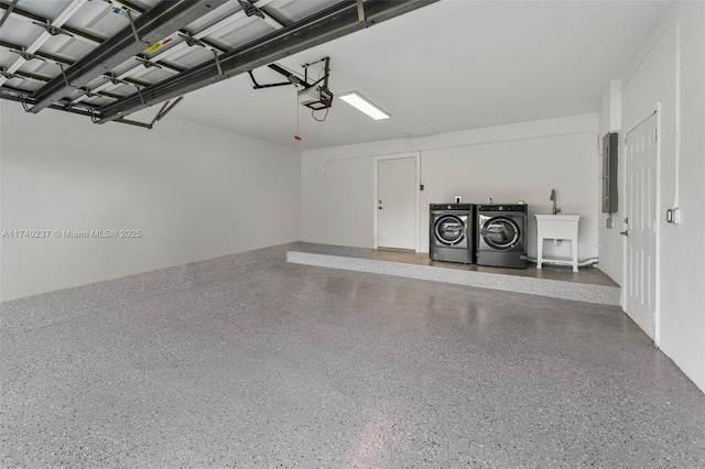 garage featuring a garage door opener, separate washer and dryer, and sink