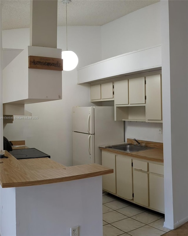 kitchen featuring white refrigerator, sink, kitchen peninsula, and cream cabinets