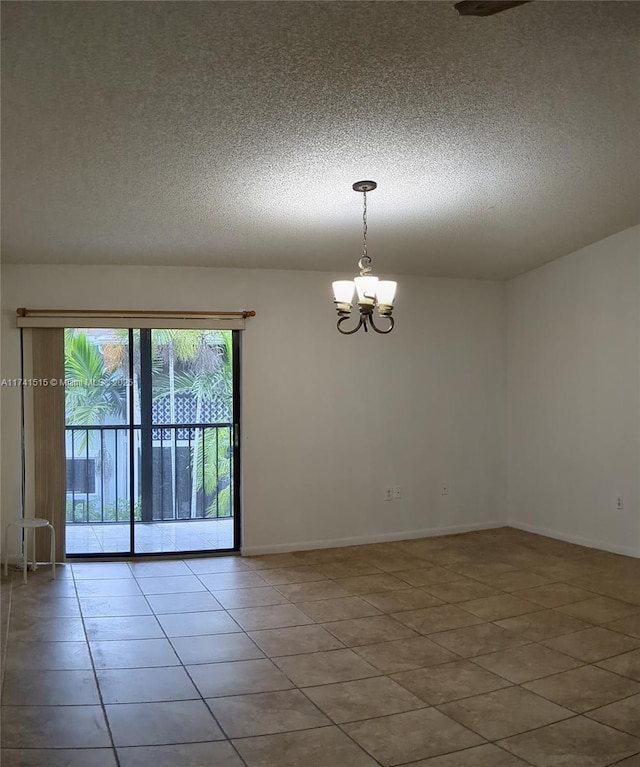 spare room with an inviting chandelier, tile patterned flooring, and a textured ceiling