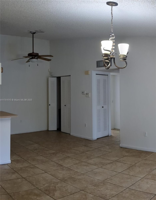 spare room featuring ceiling fan with notable chandelier and a textured ceiling