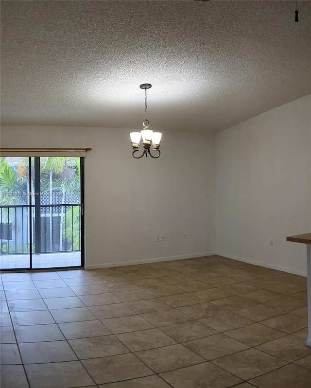 tiled spare room featuring a textured ceiling and a chandelier