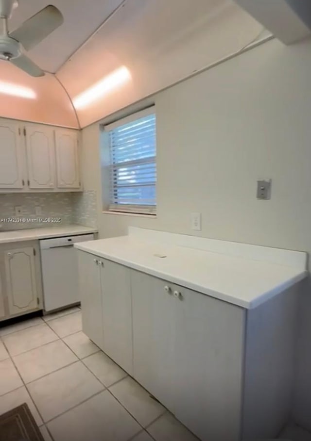 kitchen with lofted ceiling, light tile patterned floors, white dishwasher, white cabinets, and decorative backsplash