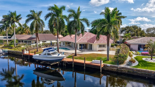 view of dock featuring a water view, a patio area, and a lawn