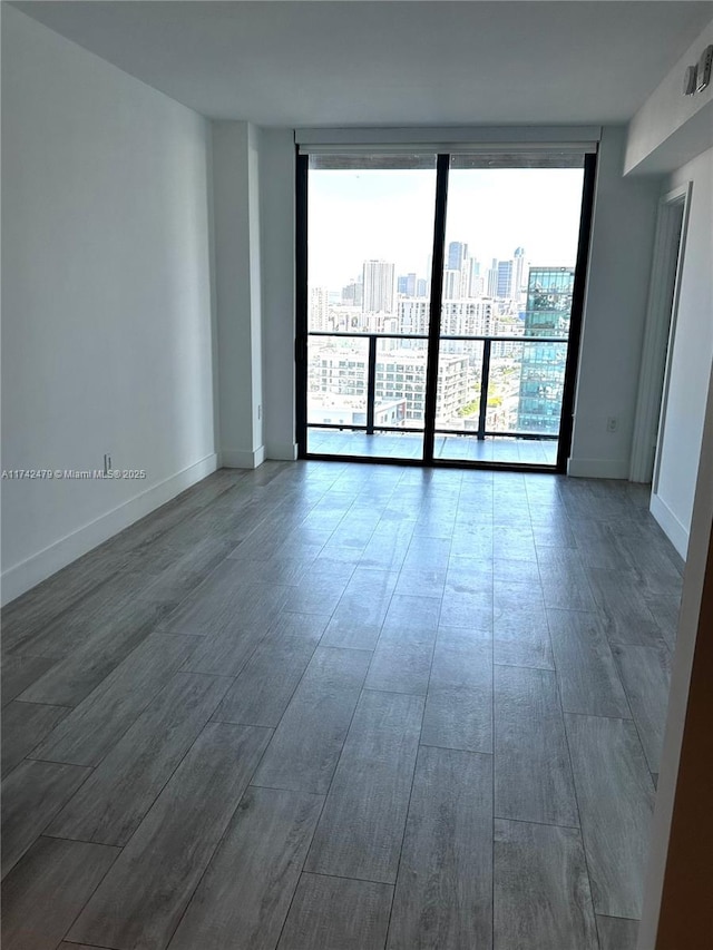 empty room featuring expansive windows and hardwood / wood-style flooring