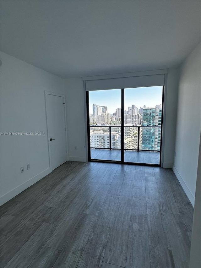 empty room featuring a wall of windows and dark hardwood / wood-style flooring