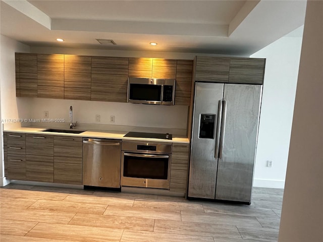 kitchen featuring appliances with stainless steel finishes, a tray ceiling, and sink