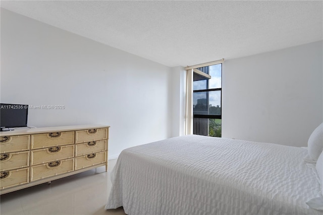 bedroom with a textured ceiling and a wall of windows