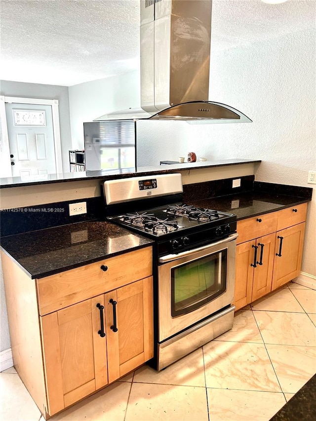 kitchen featuring dark stone counters, a textured ceiling, island exhaust hood, and gas stove