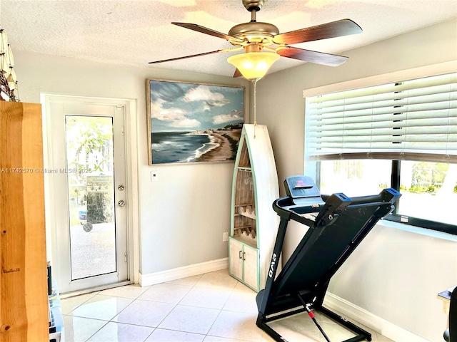 exercise area with ceiling fan, light tile patterned floors, and a textured ceiling