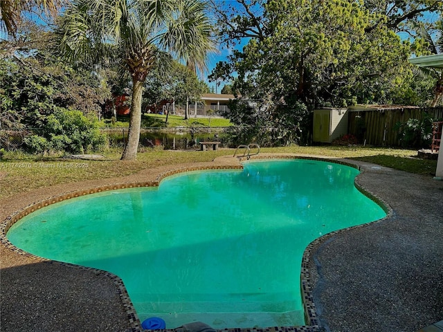 view of pool featuring a lawn and a storage shed