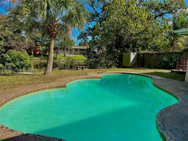 view of swimming pool with a lawn and a storage shed