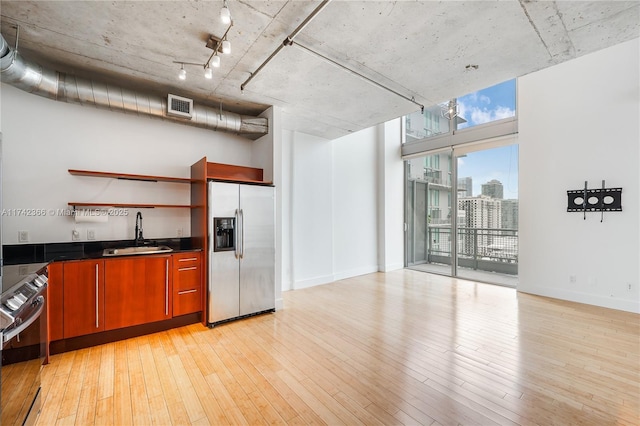 kitchen featuring rail lighting, sink, stove, stainless steel fridge with ice dispenser, and light wood-type flooring