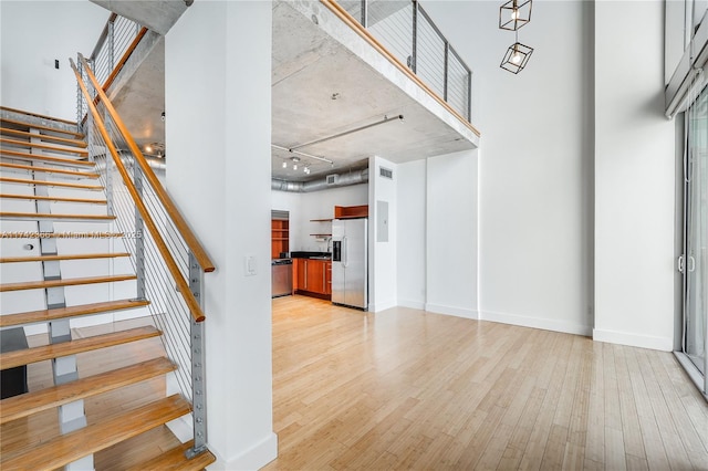 stairs featuring a towering ceiling and hardwood / wood-style floors