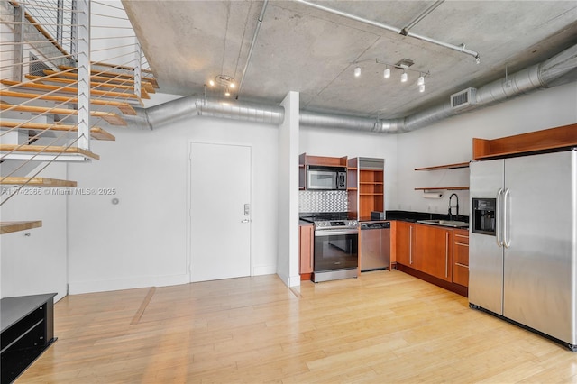 kitchen featuring appliances with stainless steel finishes, sink, backsplash, a high ceiling, and light hardwood / wood-style floors